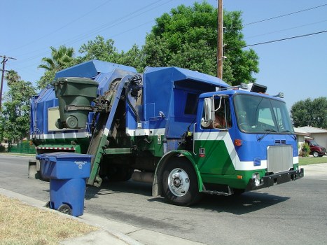 Large vehicle collecting construction waste from a shop fit-out on a busy parade